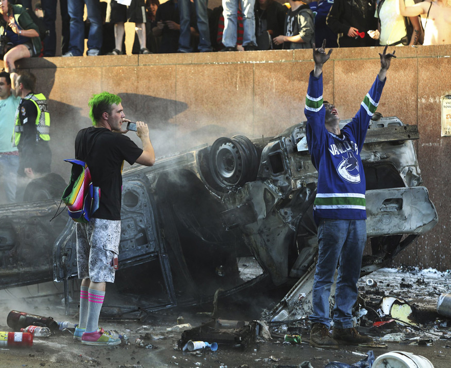 Vancouver-Riot Tank Boy Men standing in front of a burnt car